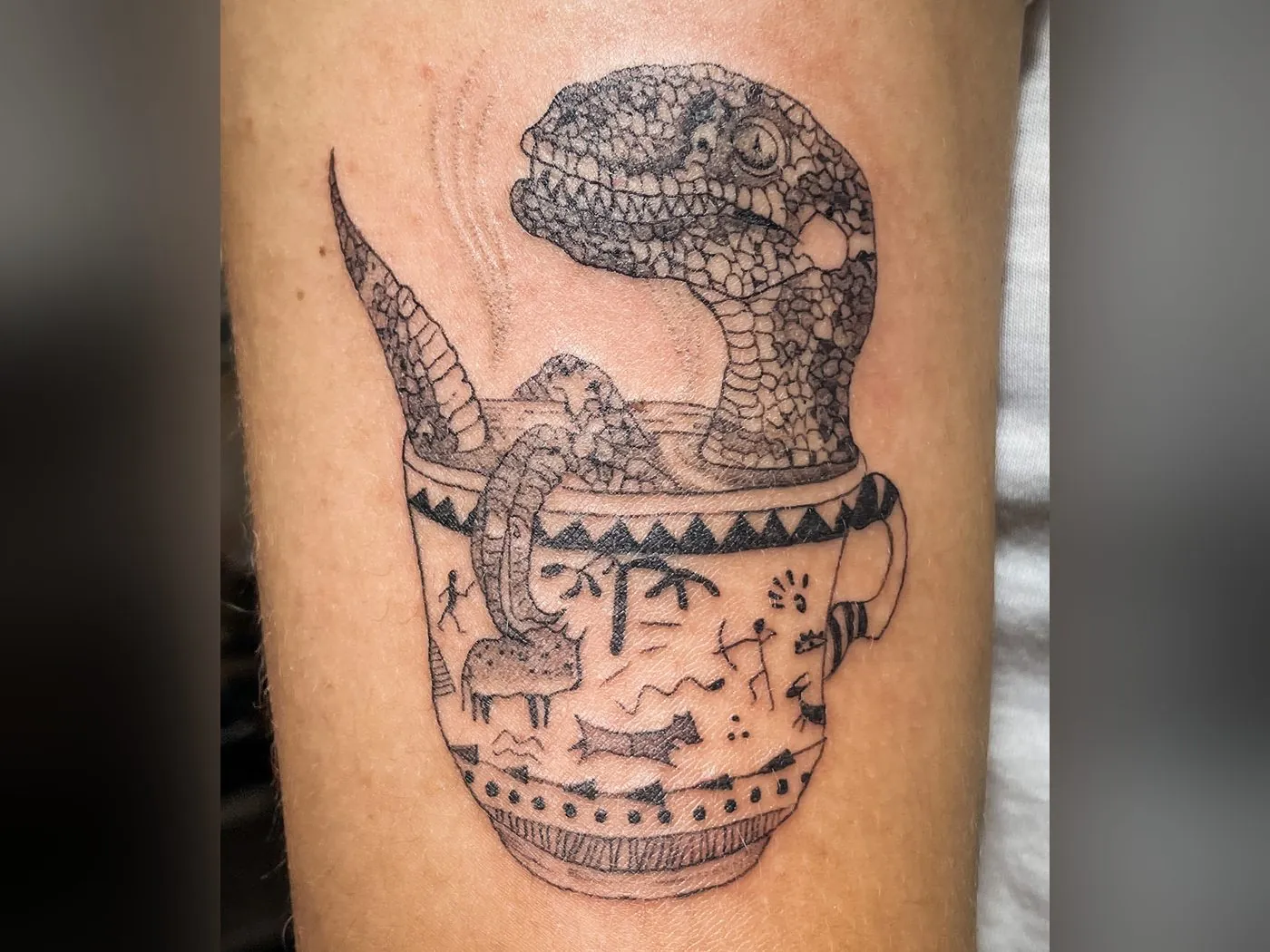 Tatuaje de raptor dentro de una taza de té, pieza original de La Logia Roma